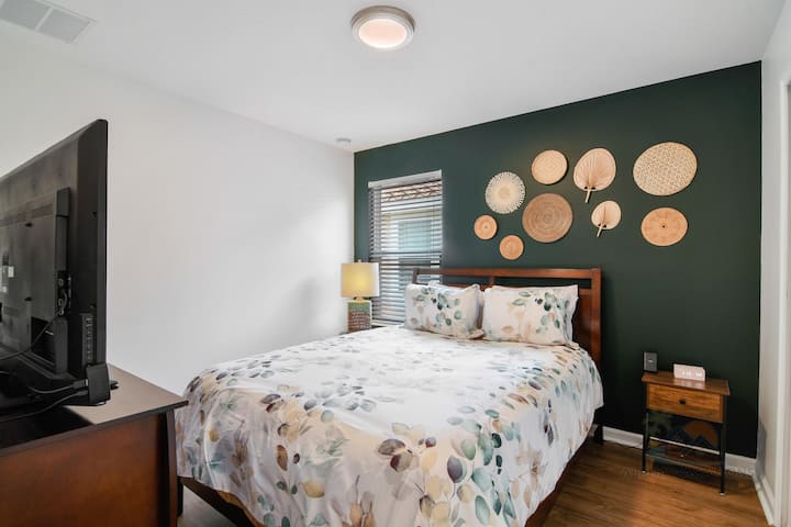 חדר שינה נעים עם עיצוב קירות אמנותי ומיטת קווין סייז קטיפה ללילות של מנוחה.