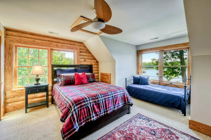 Un dormitorio encantador con una cama tamaño queen, un sofá cama y grandes ventanales que ofrecen impresionantes vistas al lago, complementado con un baño privado para mayor comodidad.