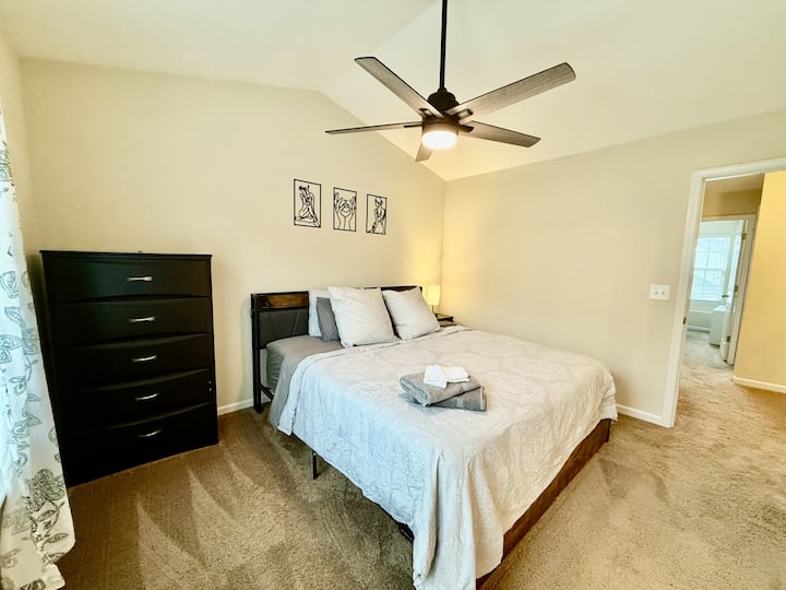 Spacious and elegant master bedroom featuring a plush king-size bed, vaulted ceilings, a smart TV, and en-suite bathroom access.