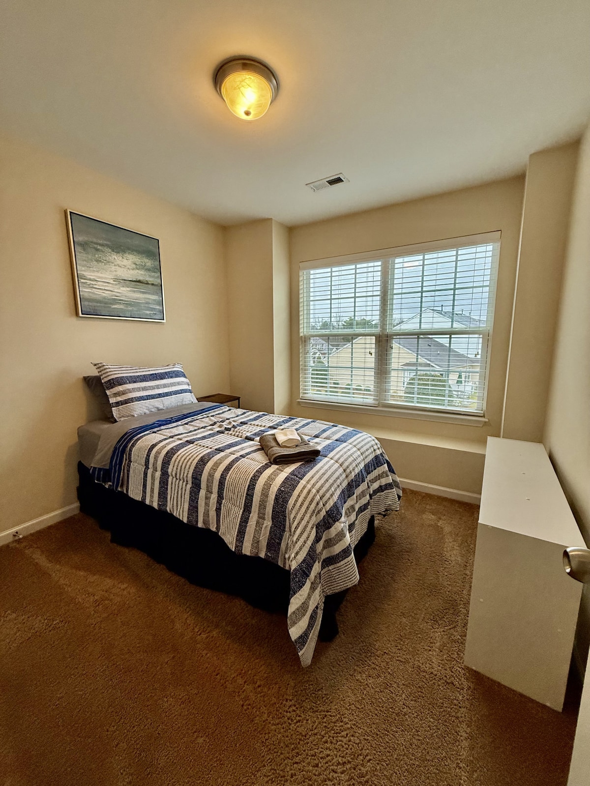 ห้องนอนที่สว่างและอบอุ่นพร้อมเตียงแฝดที่สะดวกสบายหน้าต่างบานใหญ่และการตกแต่งริมชายฝั่งที่ผ่อนคลาย