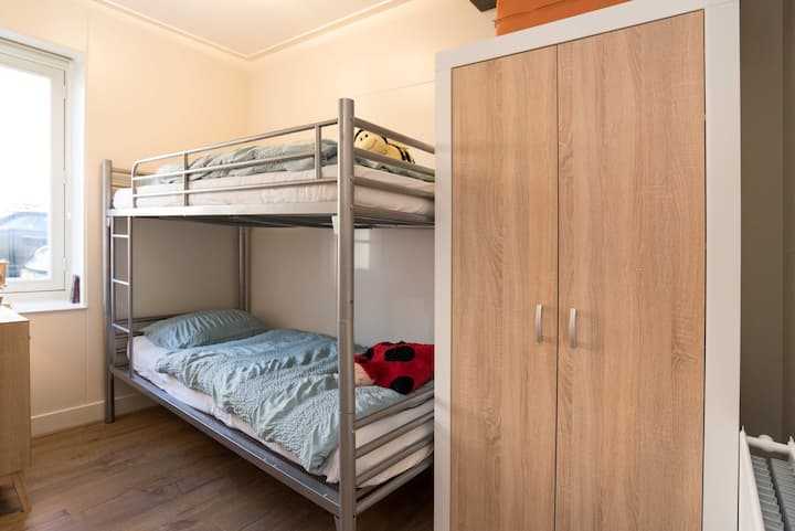 Cozy bedroom featuring a sturdy bunk bed, ideal for both children and adults, with a wardrobe for convenient storage.