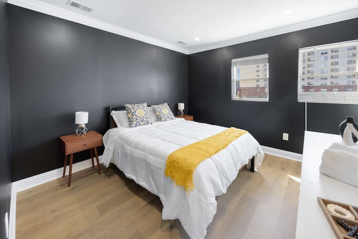 ผนังสีดำโฉบเฉี่ยวและสำเนียงสีเหลืองสดใสสร้างบรรยากาศที่หรูหราแต่อบอุ่นในห้องนอนที่กว้างขวางนี้