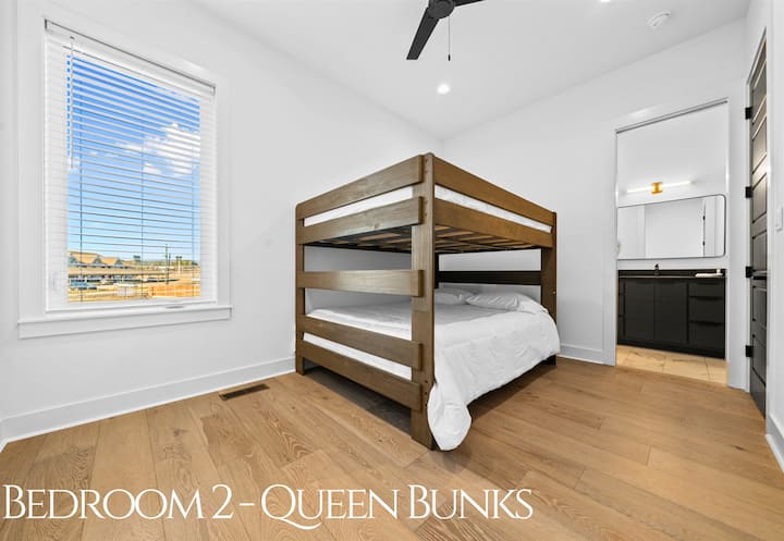 Um beliche queen luminoso e convidativo com linhas limpas, roupas de cama aconchegantes e muito espaço, projetado para fazer com que todos os hóspedes se sintam em casa.