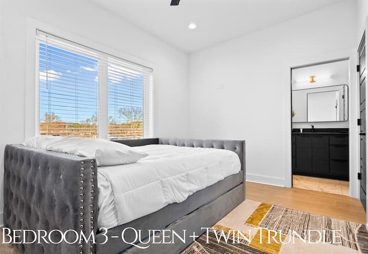 Um quarto queen flexível com um trundle duplo, decoração moderna e luz natural, criando um espaço elegante e versátil para famílias ou grupos.