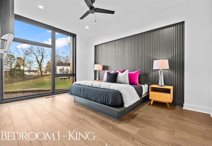 Луксозна кралска спалня със смели цветни акценти, привлекателни текстури и големи прозорци, които пропускат естествена светлина и спокойна гледка на открито.