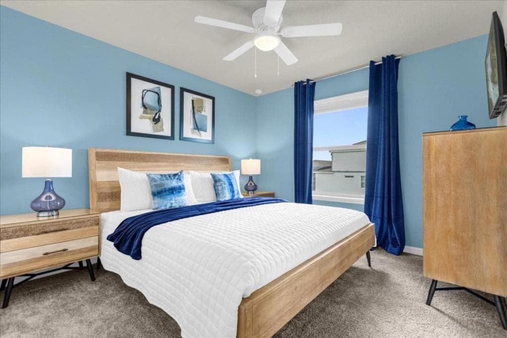 غرفة نوم مشرقة وجيدة التهوية تحتوي على سرير بحجم كينج ومفروشة بأثاث عصري مع لمسات زرقاء هادئة.