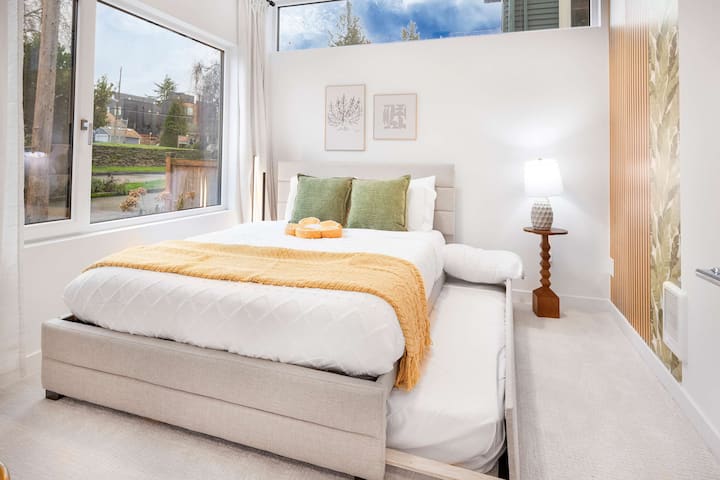 Entre em um quarto cheio de luz com roupa de cama macia e um ambiente calmante. A cama de rodízio adicional torna este quarto perfeito para famílias ou grupos. Janelas grandes oferecem vistas encantadoras do bairro, fazendo com que as manhãs pareçam brilhantes e refrescantes.