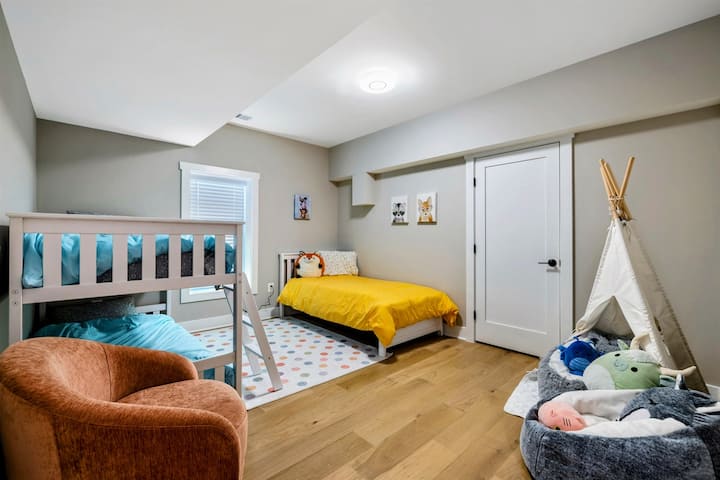 Una giocosa e invitante camera da letto per bambini con letti a castello, un letto singolo, un accogliente angolo lettura e accesso a un bagno Jack e Jill per una maggiore comodità.