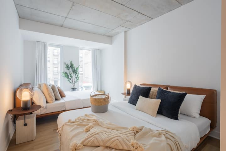 Immergiti in due comodi letti immersi nella luce naturale, completati da morbide trame e accenti premurosi per un tranquillo riposo notturno