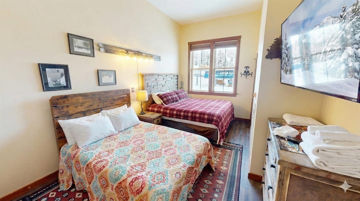 Teplá, rustikálna spálňa s manželskou posteľou King a plnými posteľami a výhľadom na hory – pohodlie sa stretáva s dobrodružstvom.