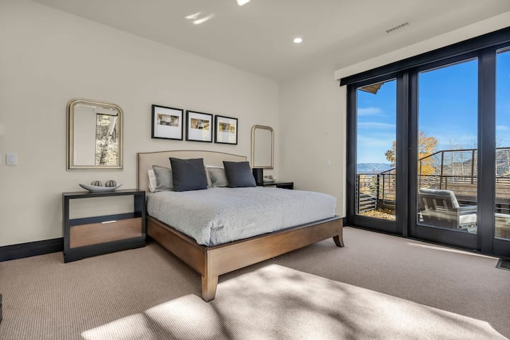 大床、床頭櫃、鏡子和通往陽台的滑動門