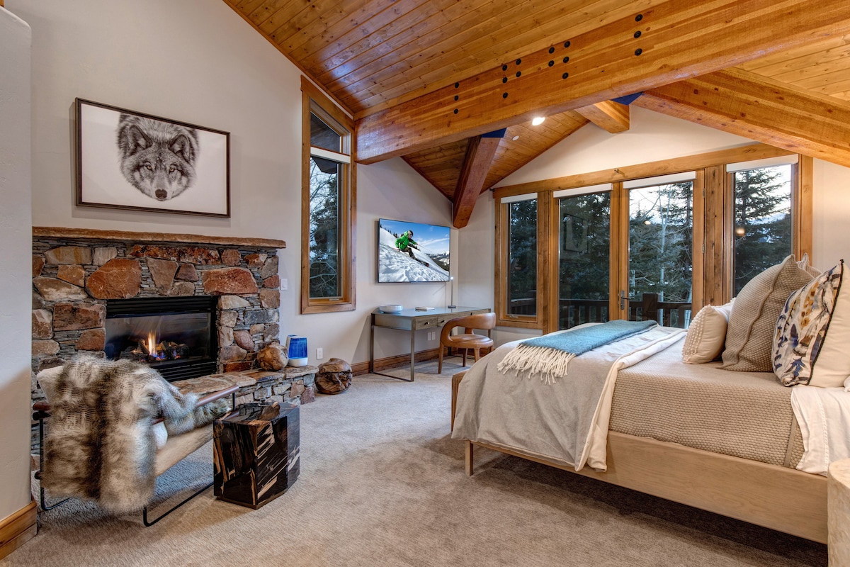 A bedroom with a fireplace, seating area, and a desk.