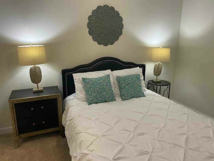 Enjoy peaceful nights in this cozy bedroom with a plush bed, soft linens, and vibrant pillows. Two stylish lamps provide a warm glow, and the elegant wall decor enhances the charm of your stay.