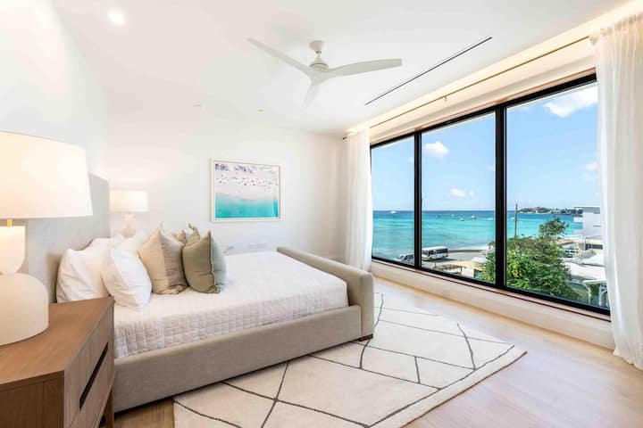 Dormitorio 1 con cama tamaño king, televisión y vistas al mar. Se proporcionan todas las sábanas y ropa de cama durante tu estadía.