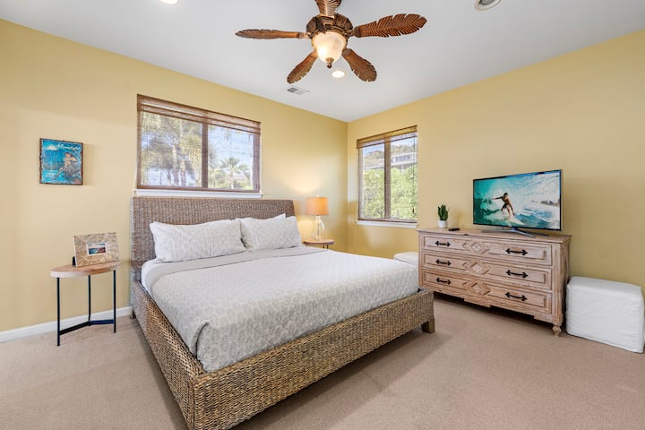 חדר שינה מואר עם מיטת קינג סייז, חלונות גדולים וטלוויזיה עם מסך שטוח למנוחה.