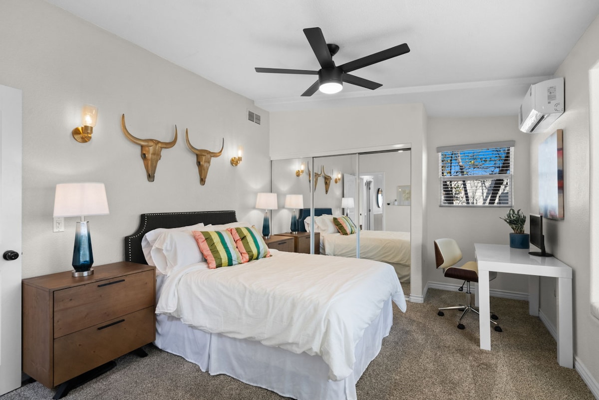 Een stijlvolle en gezellige slaapkamer met moderne inrichting, een werkplek en warme verlichting.