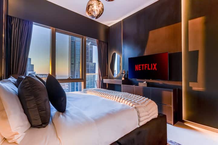 חדר שינה נעים עם טלוויזיה חכמה וחלונות גדולים המציעים נופים עוצרי נשימה של קו הרקיע של מרכז העיר דובאי, ויוצרים שילוב מושלם של נוחות ויוקרה לשהייה שלכם.