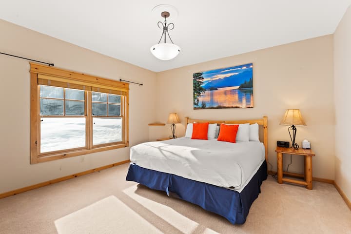 Chambre principale de niveau inférieur avec un grand lit king size et une salle de bains privative. 