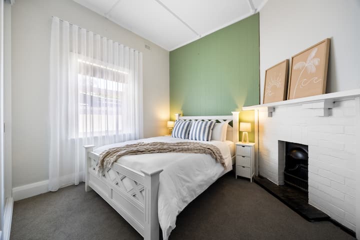 柔和的绿色背景与明亮的白色家具和复古风格的壁炉形成了鲜明的对比。