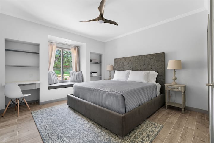 Elegante dormitorio con una cama tamaño king con una cabecera única con textura de madera.