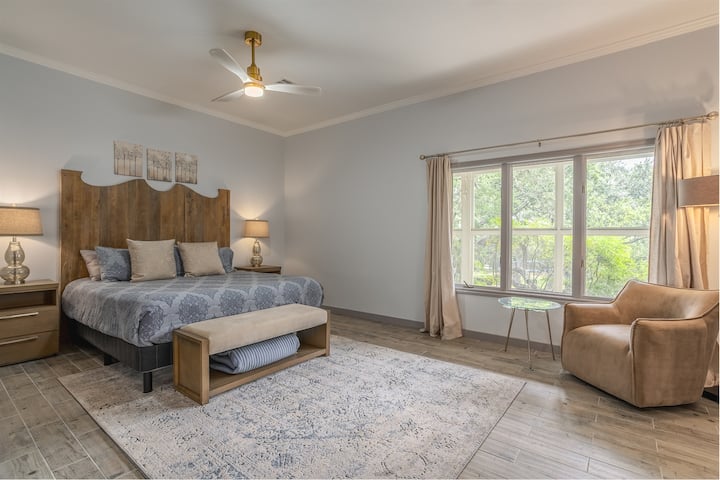 Amplio dormitorio principal con cama king, decoración elegante y una vista apacible.