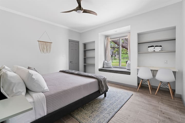 Dormitorio espacioso y elegante con una cama tamaño king y un acogedor asiento en la ventana.