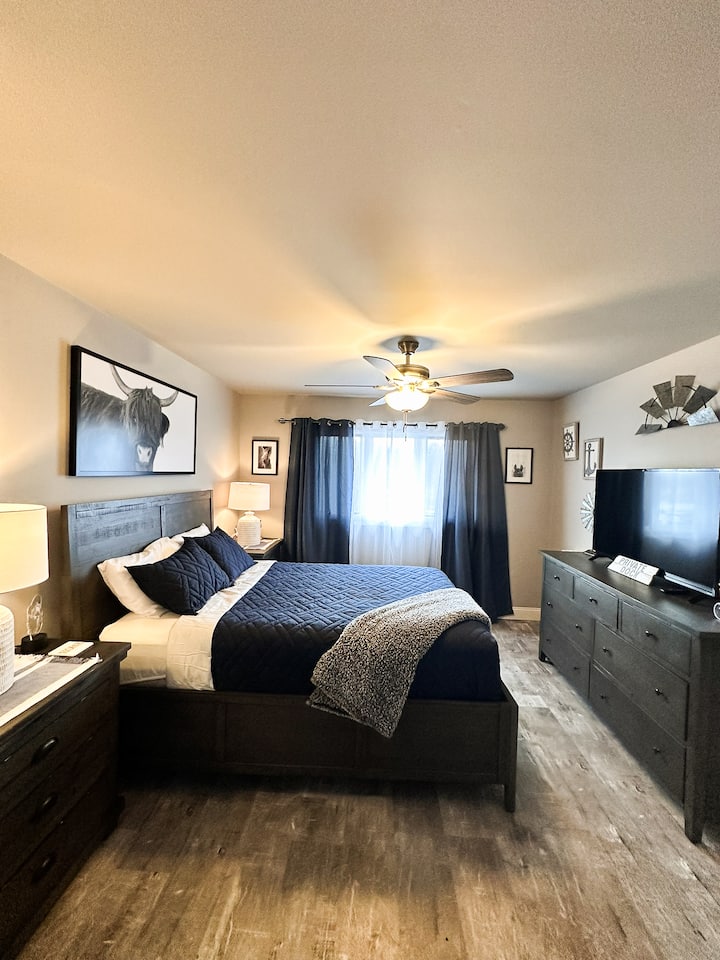 تتميز غرفة النوم هذه بسحر ريفي حديث مع أثاث خشبي داكن وغطاء سرير بحري فخم وضوء طبيعي ناعم يتم ترشيحه من خلال ستائر التعتيم - وهو مثالي للراحة والاسترخاء.