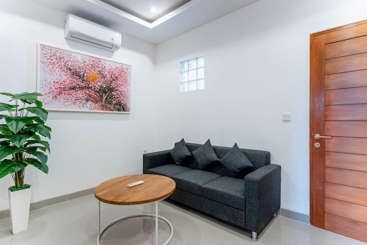 Útulná obývacia izba so štýlovou pohovkou, televízorom s plochou obrazovkou a nástenným umením. Ideálne miesto na oddych alebo filmový večer v interiéri.