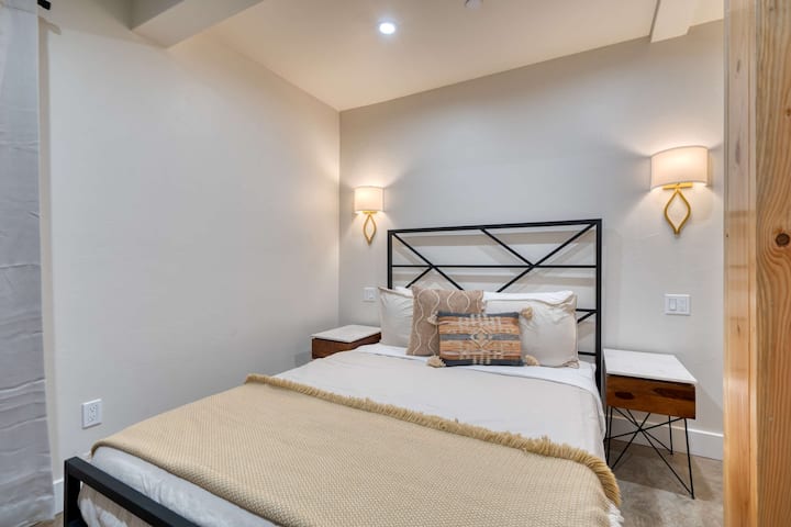 Bedroom with a metal bed frame and wall-mounted bedside lamps.