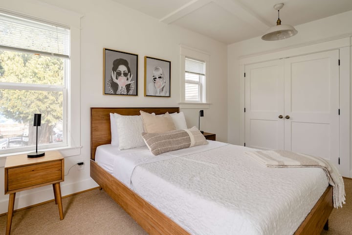 Bedroom with wooden bed frame and framed portrait art.