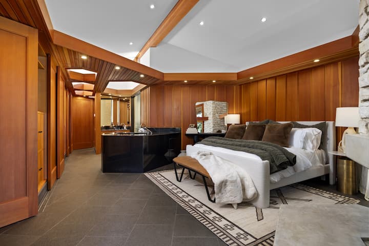 Tyylikäs makuuhuone, jossa on lämpimät puupaneelit ja pehmeä vuode.