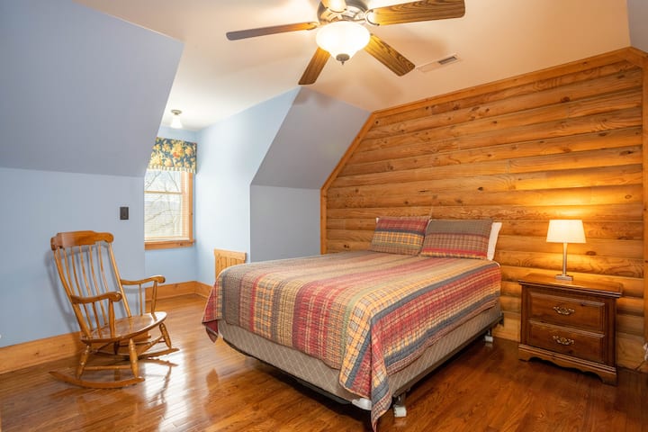 ห้องนอนกว้างขวางเน้นไม้อบอุ่นเตียงนอนสบายและเก้าอี้โยกคลาสสิกริมหน้าต่างสำหรับช่วงเวลาที่เงียบสงบ