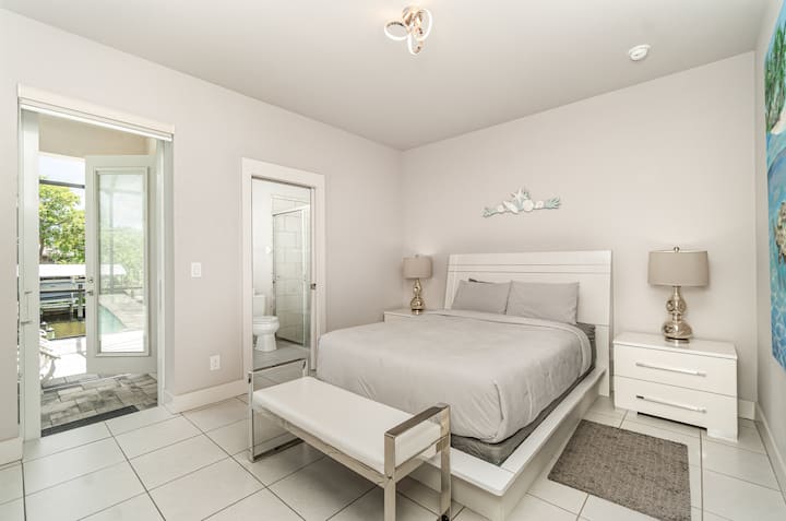Acogedor dormitorio con cama tamaño queen y acceso directo al patio al aire libre, con baño privado.