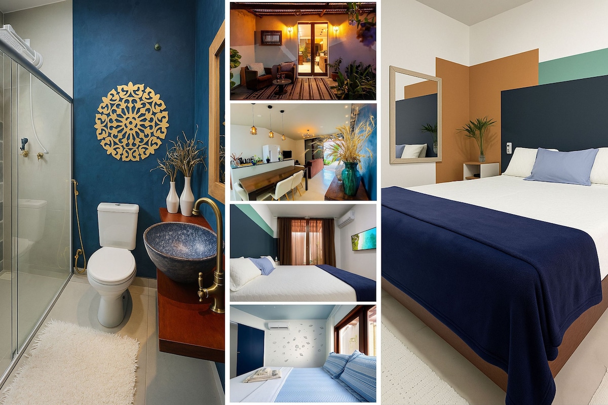 A refreshing bathroom features a glass shower with modern fixtures and a stylish blue sink. A cozy bedroom showcases a spacious bed with blue and white linens, complemented by warm accent walls. An integrated living area reveals a welcoming atmosphere with tasteful decor.