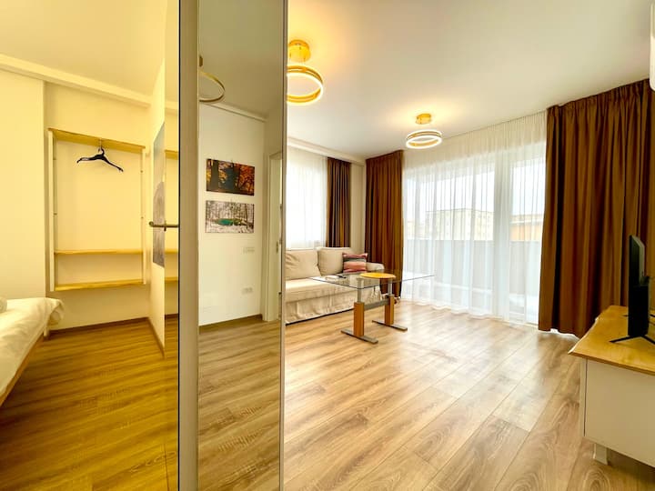 Всекидневна, която предлага разтегателен диван с декоративни възглавници, смарт телевизор с достъп за стрийминг, маса, климатик и затъмняващи щори в стаята