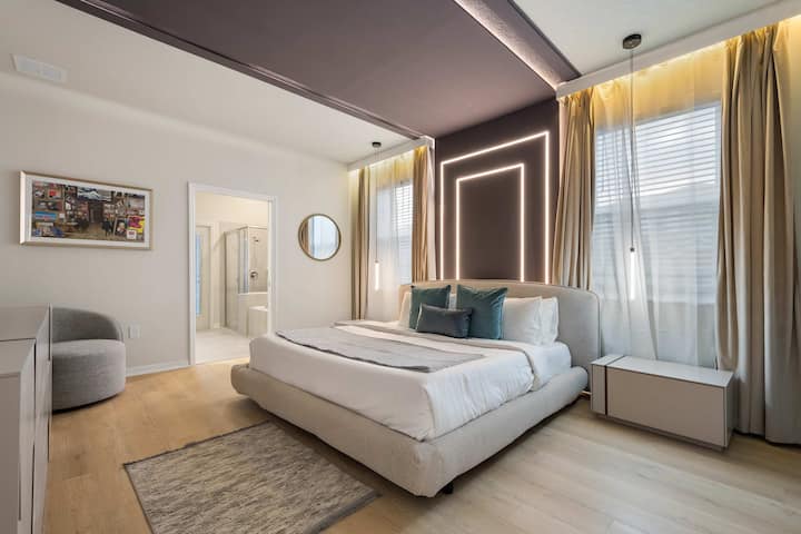 Suite contemporánea con cama tamaño king, pared decorativa brillante y baño estilo spa.