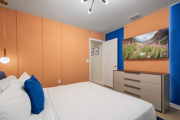 Dormitorio vibrante con paredes decorativas audaces, cama acogedora y TV inteligente grande.