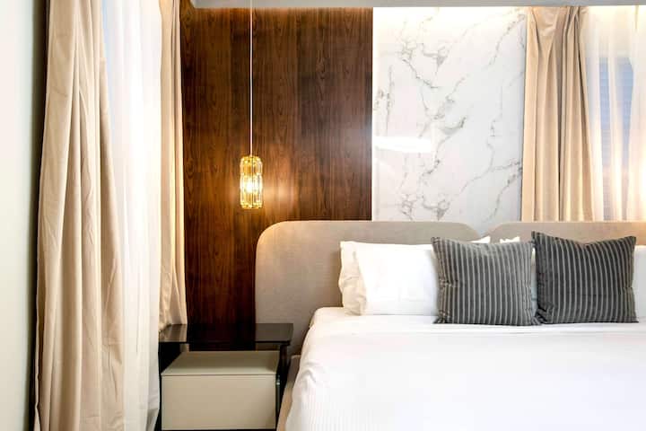 Dormitorio moderno y minimalista con iluminación elegante, detalles de mármol y tonos neutros