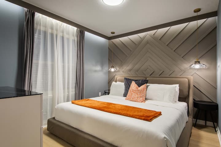 Elegante dormitorio con moderna pared decorativa de madera, acogedora cama tamaño king e iluminación suave.