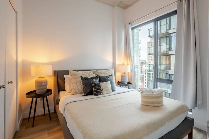 Მშვიდი საძინებელი რბილი ტონებითა და ქალაქის ხედებით.