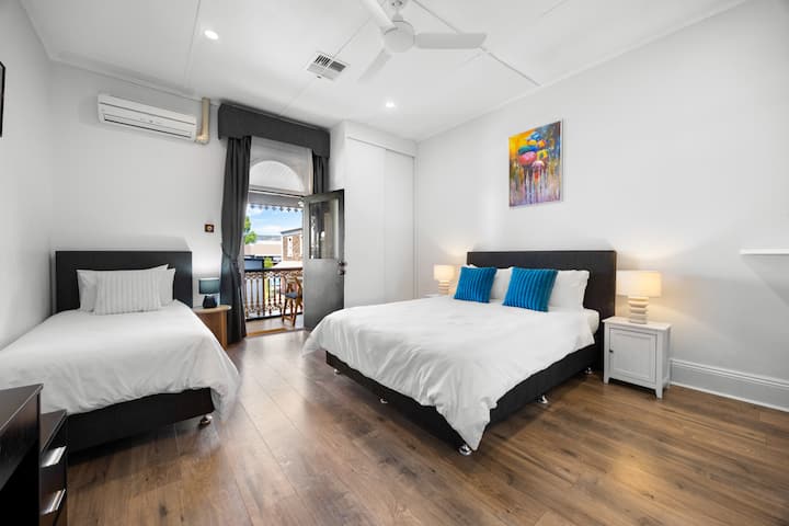 Une chambre bien éclairée et accueillante avec un lit king size à côté d'un lit simple.