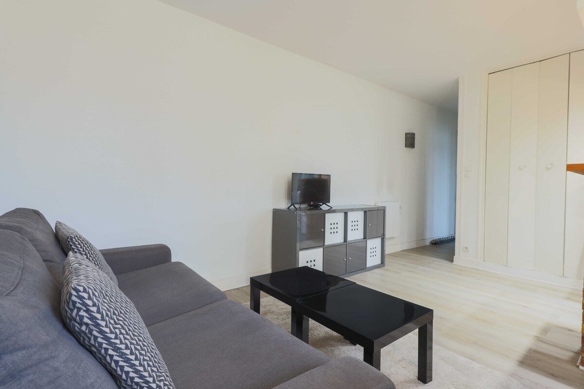 Dnevni boravak s kaučem na razvlačenje, TV-om i stolom za blagovanje.