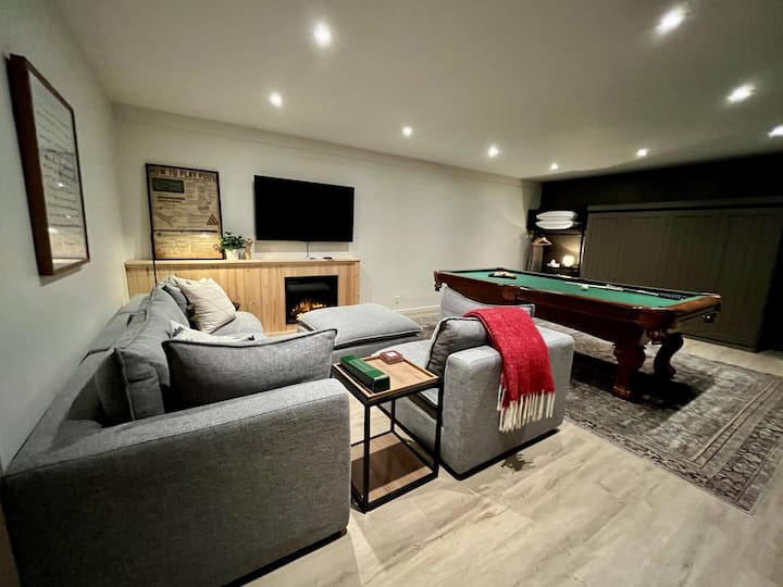 Le Salon - Salle de Jeux au sous-sol. 
Au fond le lit Queen escamotable,
La table de billard et l'espace salon avec télé intelligente et foyer électrique.