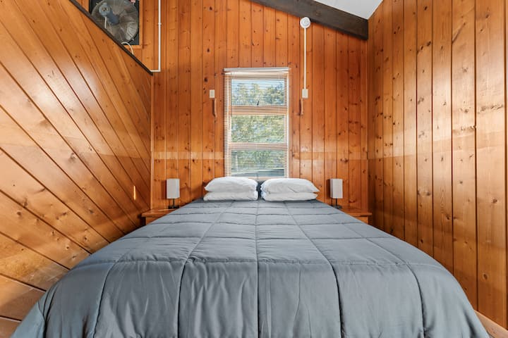 Acogedor dormitorio queen con paredes rústicas de madera, un entorno tranquilo para una gran noche de sueño.