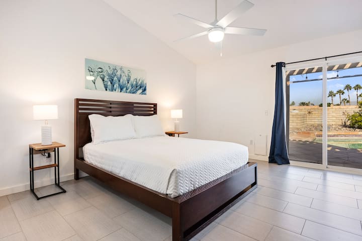 Dhomë gjumi e gjerë për vizitorë me çarçafë të bardhë dhe qasje në oborrin e shtëpisë.