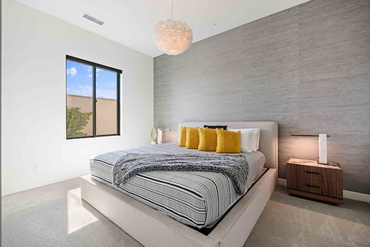 Suite 2: segundo dormitorio con pared decorativa texturizada y toques de amarillo mostaza.