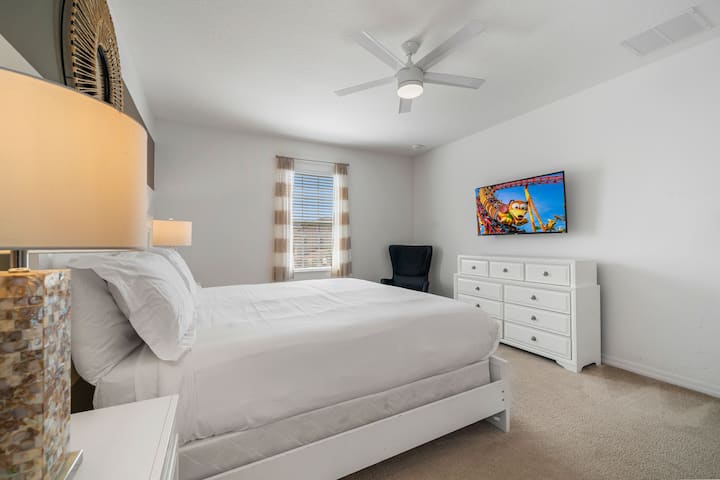 - Светла главна спалня с голямо двойно легло и свеж бял декор  
– Телевизорът и тоалетката създават уютно място за почивка в Орландо  
- Подходящо за семейства място под наем близо до Дисни със самостоятелна спалня