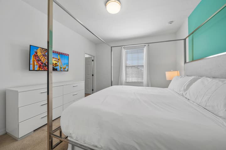 - Просторна спалня с голямо двойно легло и смела синьо-зелена акцентна стена  
- Включени са смарт телевизор и тоалетка за удобство на гостите  
– Ваканционно жилище под наем в Орландо близо до Дисни с модерна спалня
