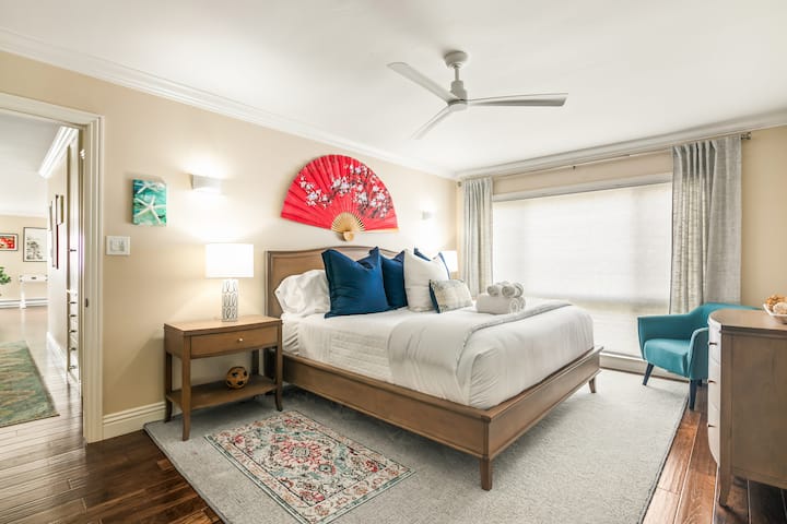 宁静的主套房，配备豪华床上用品和迷人的海滨装饰。