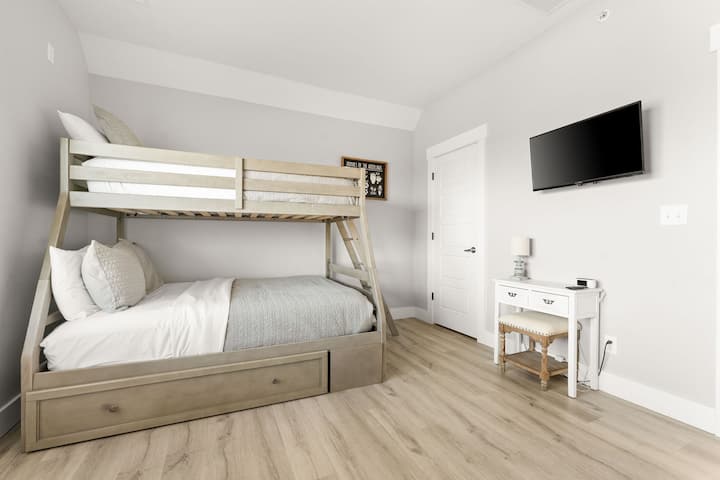 - Удобен кревет на спрат со двоен и полн кревет, идеален за филмски вечери
- Ѕиден телевизор и шармантен простор на бирото со меко столче за дополнителна удобност
- Неутралните тонови и меката постелнина создаваат мирен простор за спиење